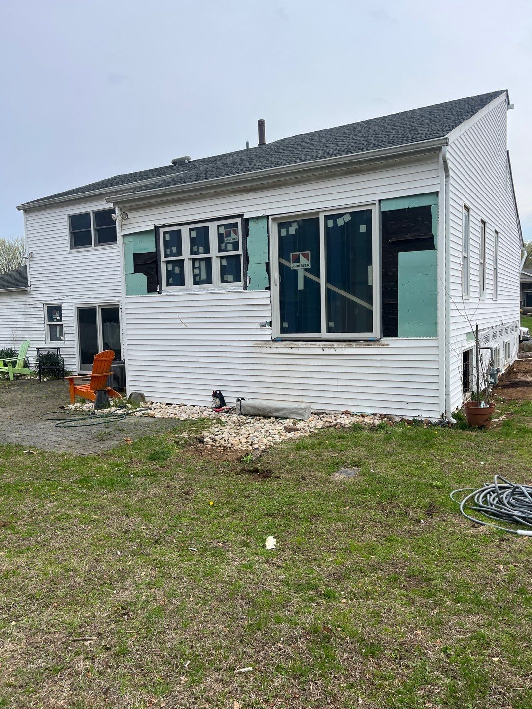 Reconstruction services two-story residential property exterior Manalapan Township with window protection and complete demolition materials visible